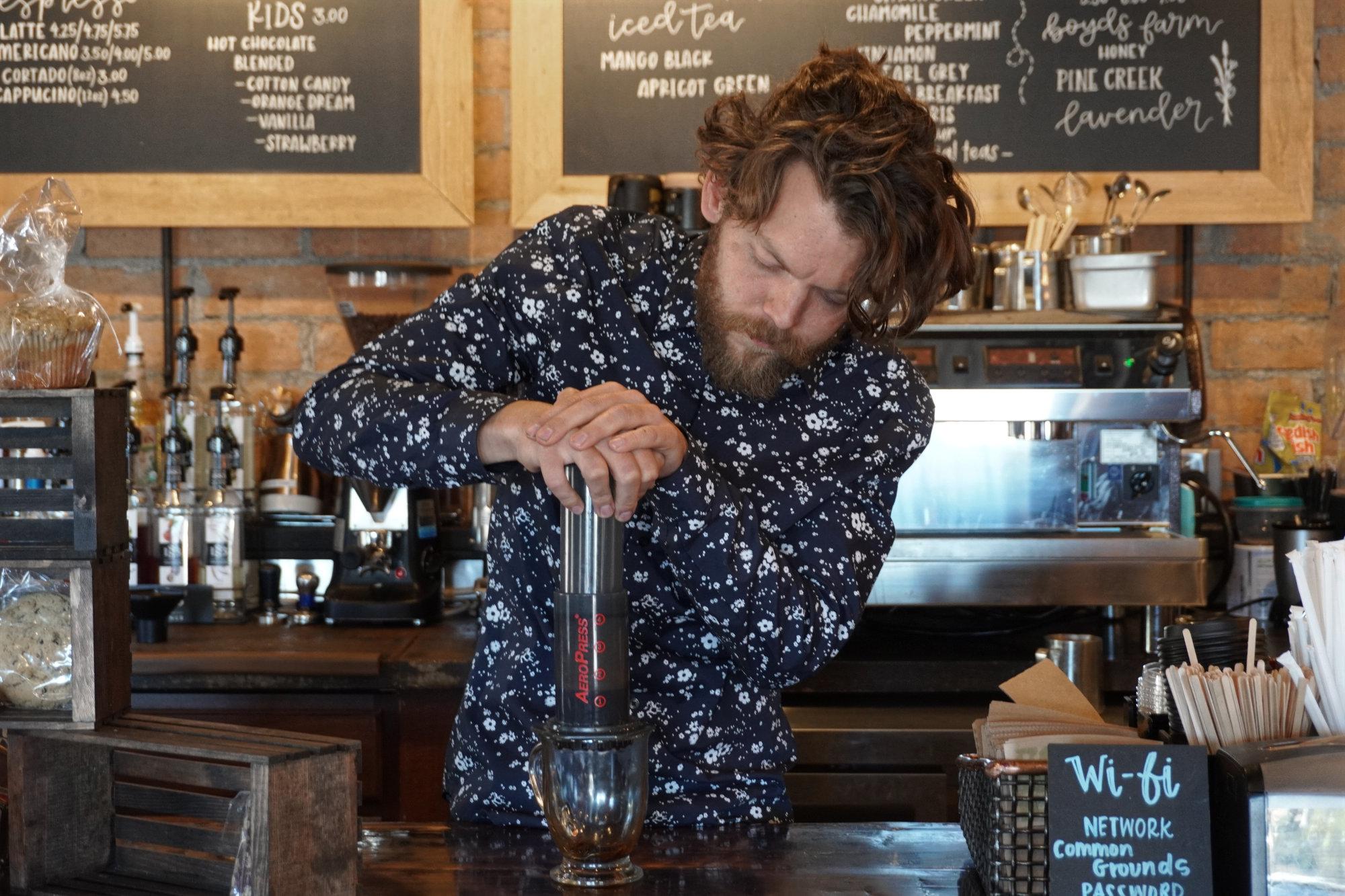 La mano de barista está poniendo granos de café en una báscula digital para  medir el peso tostado ligero