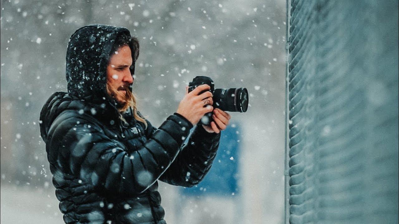 Peter McKinnon holding a DSLR camera with a Canon RF 15-35mm f/2.8 L IS USM lens